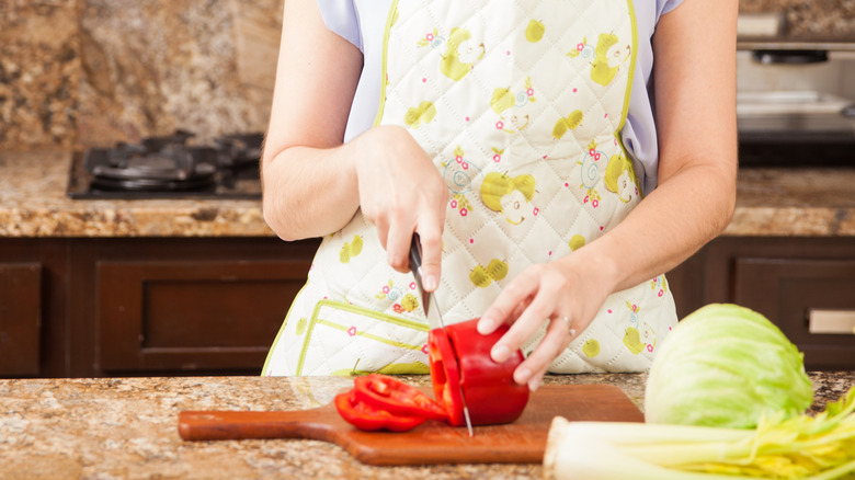 A person cutting a tomato on a cutting board