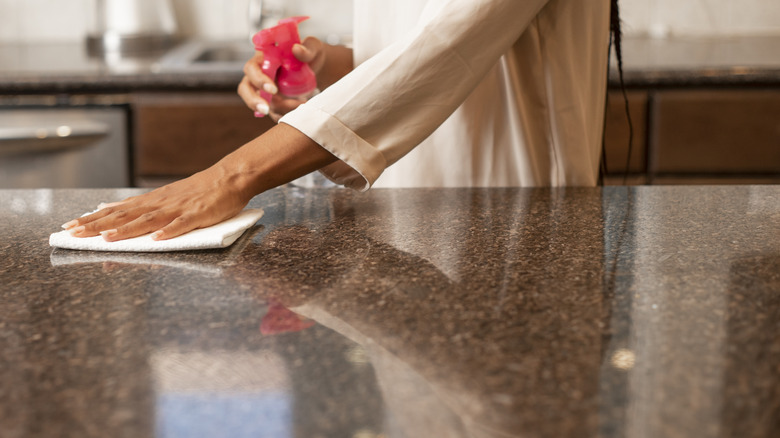 A person cleaning a granite countertop