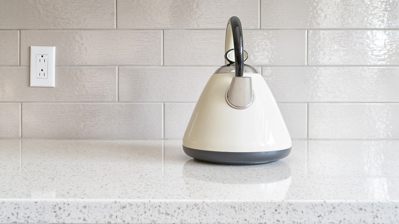 A white kettle on a granite countertop