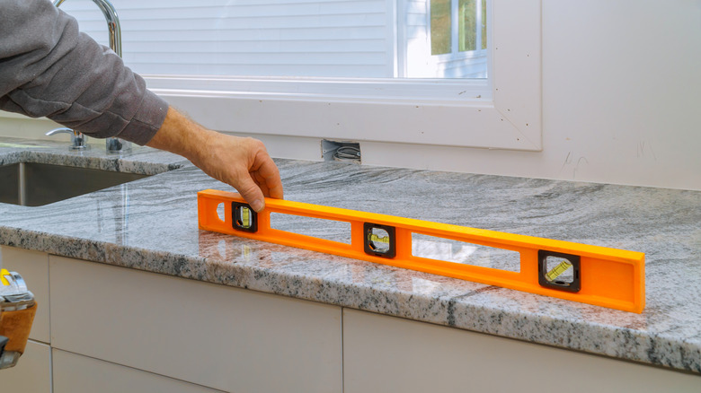A person checking that granite countertops are level