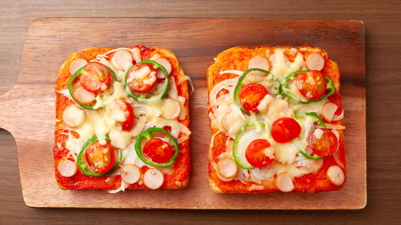 Two slices of Japanese pizza toast topped with melted cheese, tomatoes, and sliced green peppers