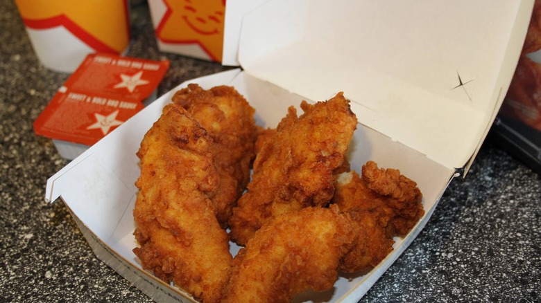 Container of Carl's Jr. chicken tenders with dips on the side