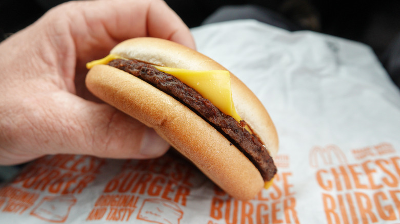 man holding McDonald's cheeseburger