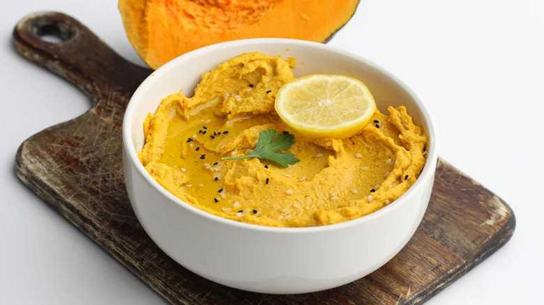 Easy Roasted Pumpkin Hummus in white bowl on wooden cutting board