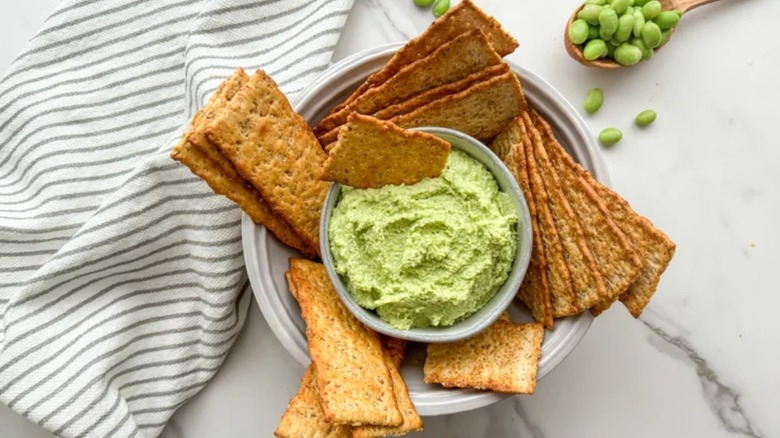 Crackers in a bowl with edamame bean hummus