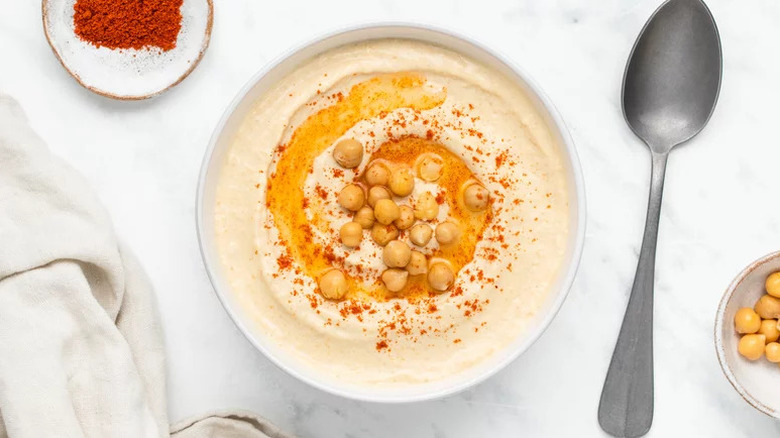 Simple Creamy Hummus in white bowl next to spoon