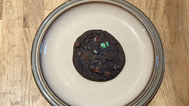Overhead image of dark chocolate mint cookie on a plate on a wooden counter