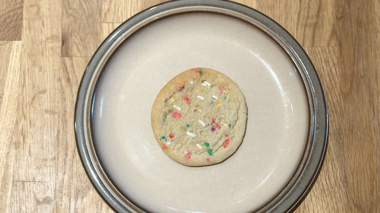 Overhead image of sprinkle cookie on a plate on a wooden counter