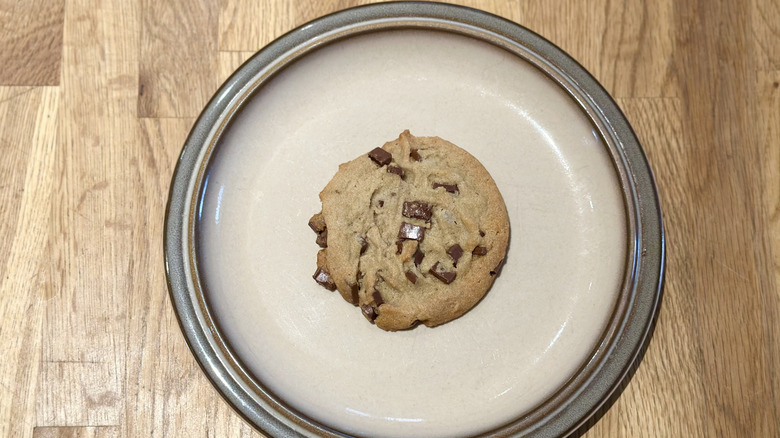 Overhead image of chocolate chip cookie on a plate on a wooden counter
