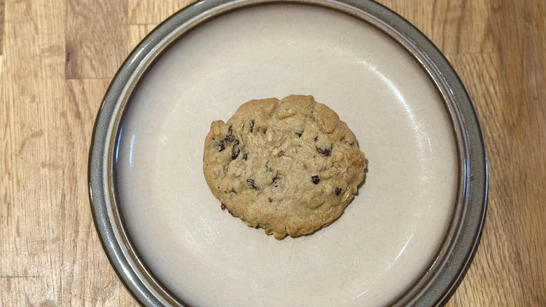 Overhead image of oatmeal raisin cookie on a plate on a wooden counter