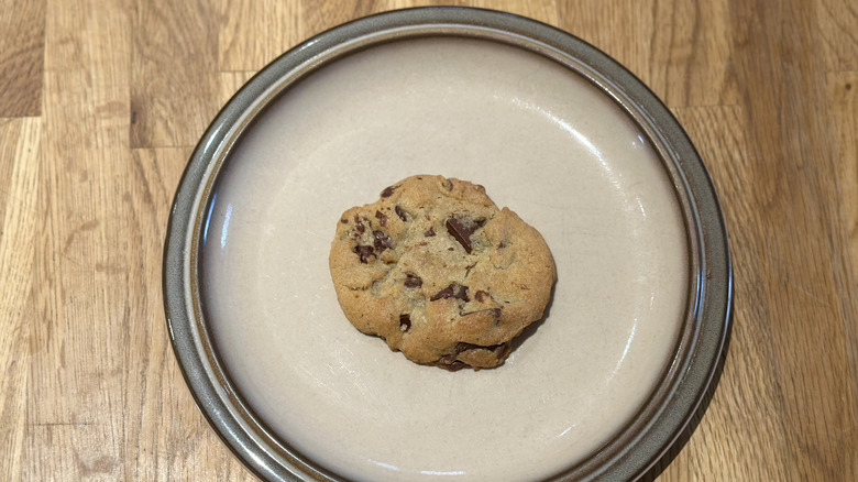 Overhead image of chocolate chunk cookie on a plate on a wooden counter