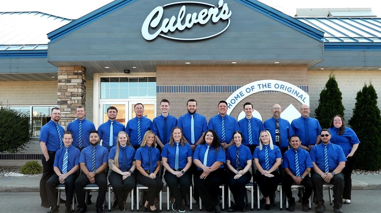 Culver's employees in blue shirts smiling in front of Culver's
