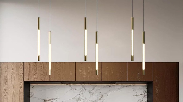 Flute-shaped pendant lamps with gold accents hanging from ceiling