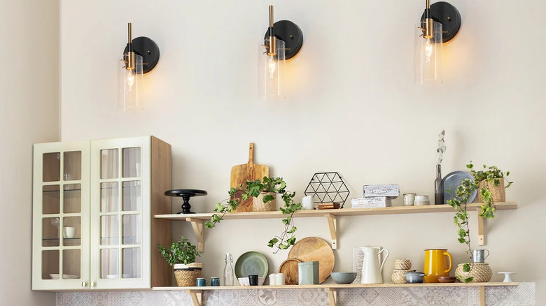 Three black glass sconce lights on white wall in natural style kitchen