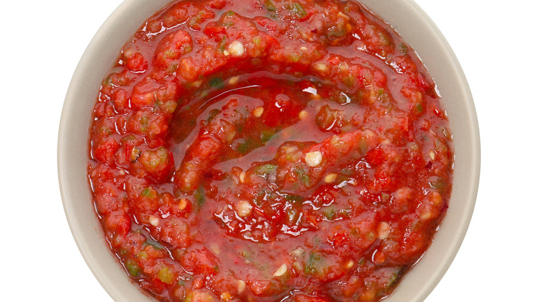 A close-up of a bowl of salsa isolated on a white background