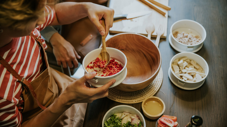 A man scoops seasoning from a bowl to add to a recipe
