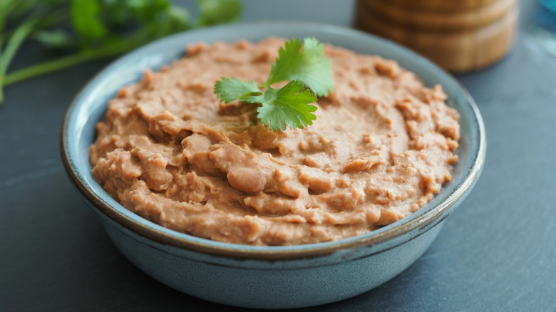 Refried beans in grey bowl with green garnish