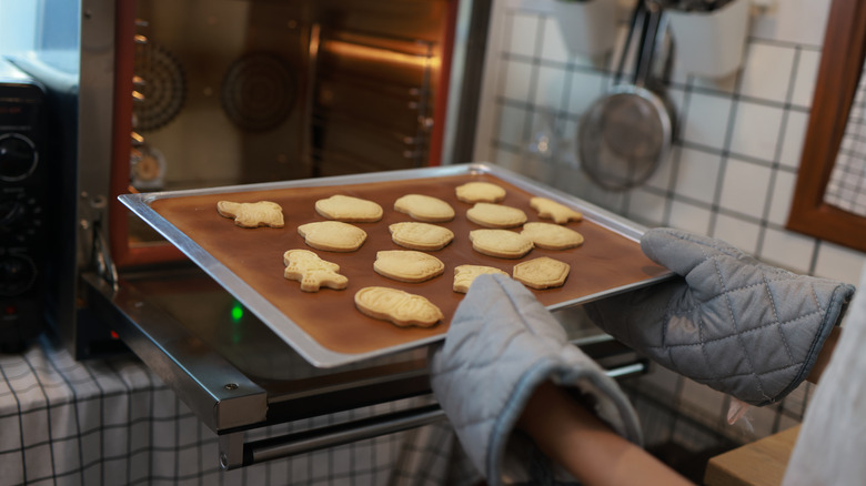 Cookies on baking mat being taken out of the oven