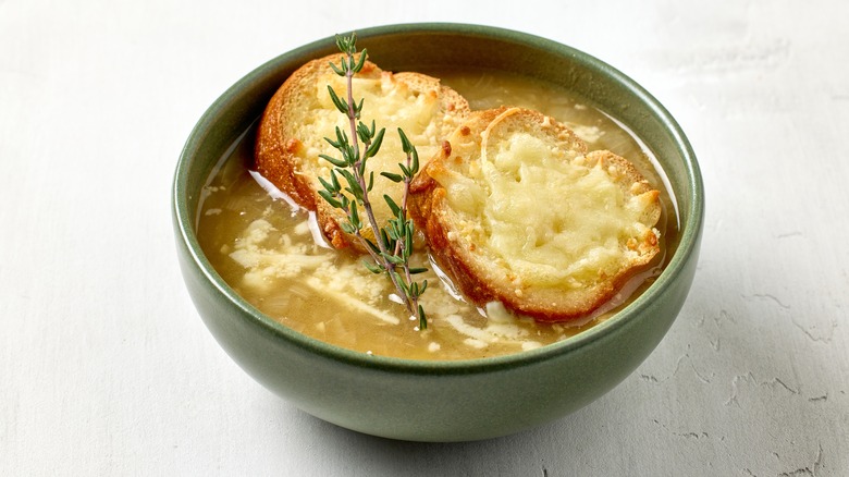 Green bowl of French onion soup with slices of bread covered in cheese