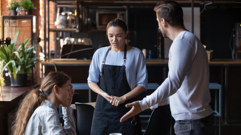 Two customers arguing with waitress in restaurant