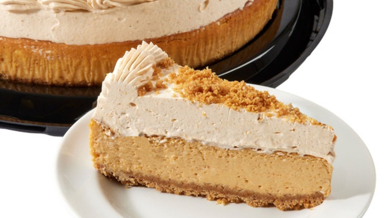 Slice of pumpkin cheesecake on plate alongside full cheesecake on platter