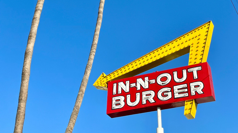 An In-N-Out sign with a large yellow arrow