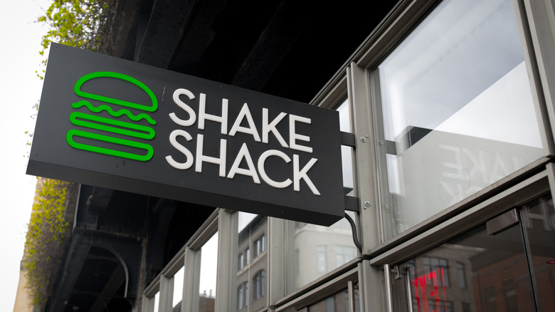 A Shake Shack sign with its green burger logo