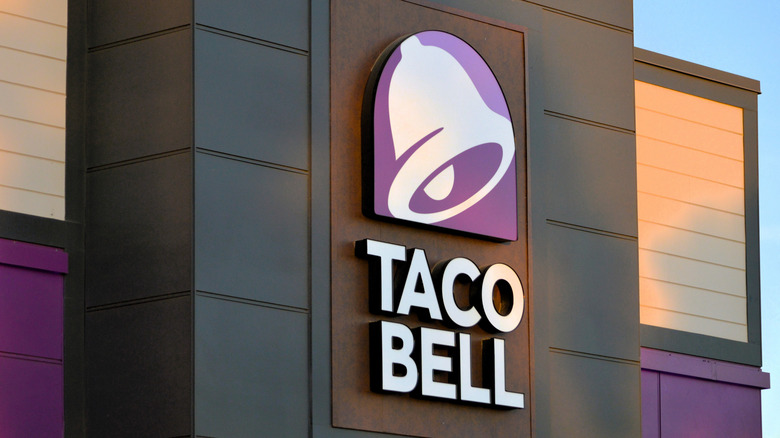 A Taco Bell sign with a purple and white bell