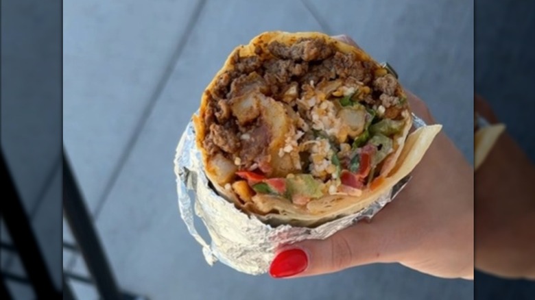 A person holding half a stuffed burrito