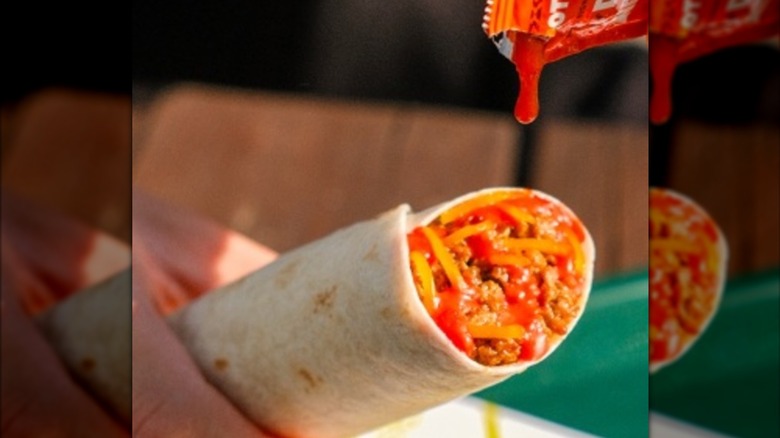 Hot sauce dripping on a Del Taco Flamin' Hot Queso burrito