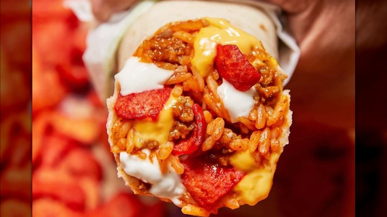 A Taco Bell Beefy Crunch Burrito with visible beef, rice, cheese, source cream, and Flaming Hot Fritos