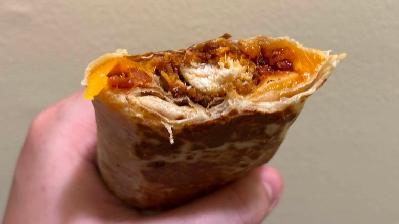 A Crispy Chicken Chipotle Bacon Melt Burrito with a bite taken out of it
