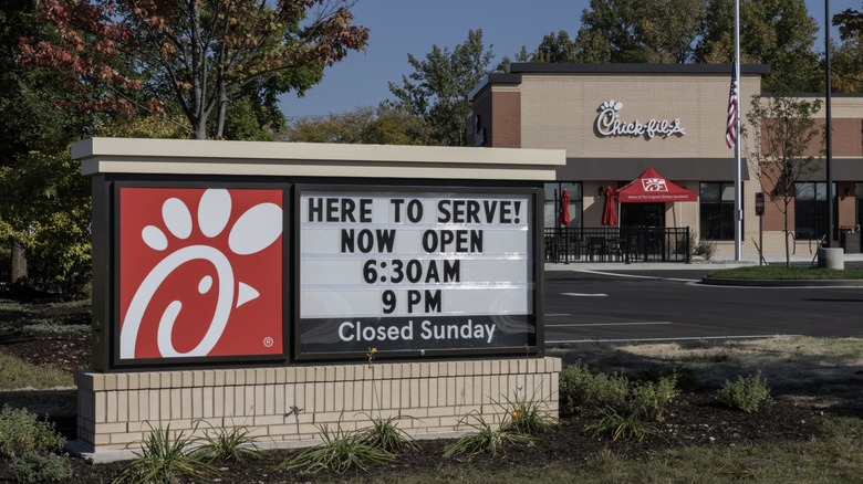 Chick-fil-A chicken restaurant with sign outside that reads "Here to serve! Now open 6:30AM 9PM Closed Sunday"