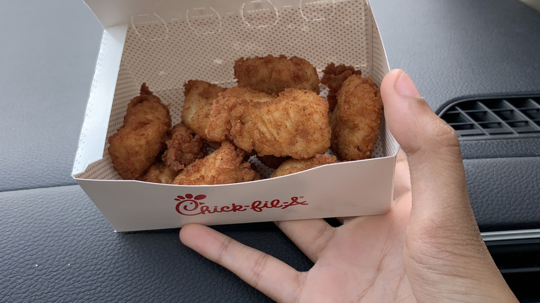 Close up of hand holding Chick-fil-A nuggets in a box in a car
