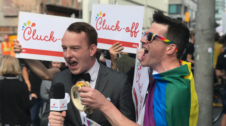 Protestors outside Chick-fil-A holding "Cluck-off" signs and wearing rainbow pride attire
