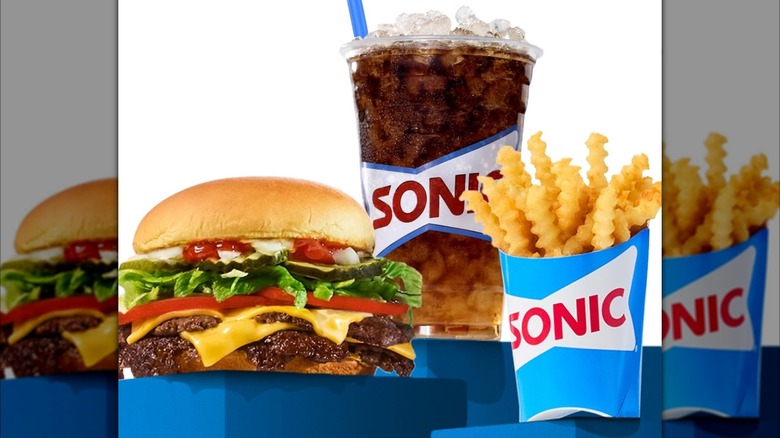 All-American Sonic Smasher burger next to sleeve of crinkle cut french fries and cup of cola soda