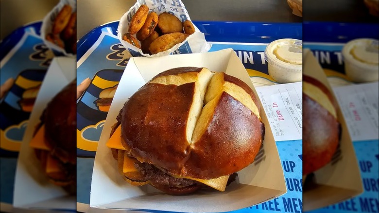 Culver's Fried Pickle Pub Burger next to paper bag of fried pickles on blue dining tray