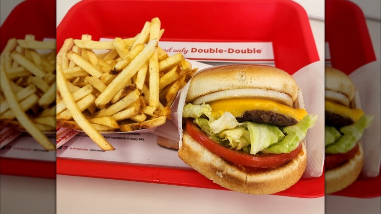 In-N-Out Cheeseburger next to serving of french fries on red dining tray