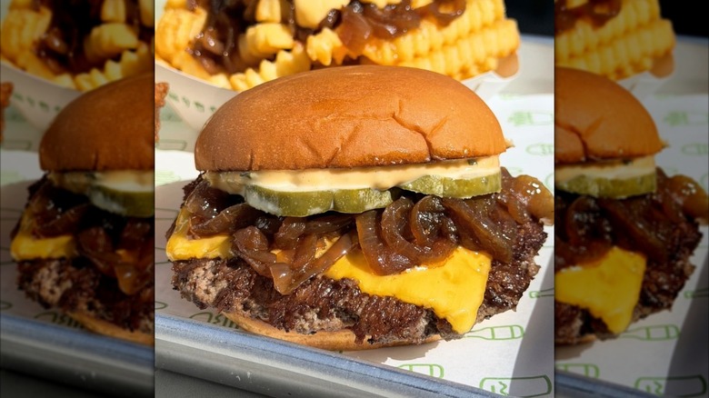 Shake Shack West Coast Burger with pickles, cheese, and sauce on dining tray