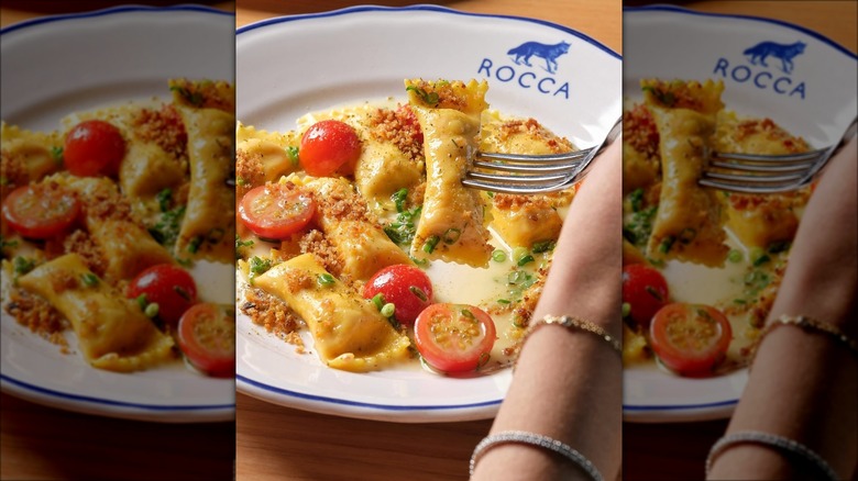 Hand using a fork to hold agnolotti from a Rocca plate