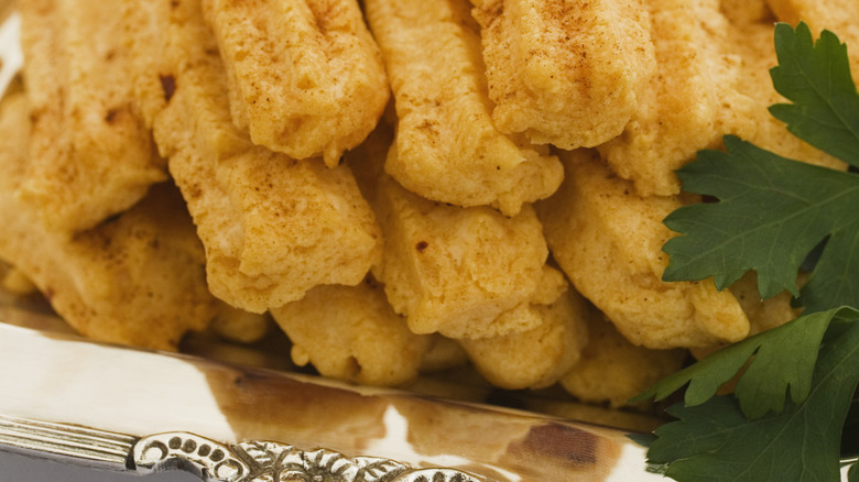 Close-up of cheese straws on silver tray.