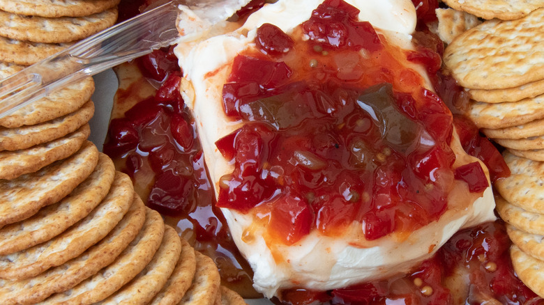 Cream cheese block with pepper jelly on top and crackers surrounding it.
