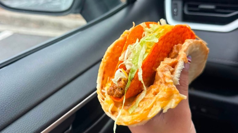Hand holding a Doritos Cheesy Gordita Crunch  made with a 3 cheese chicken flatbread melt