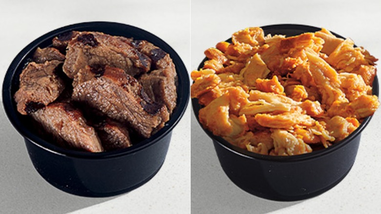A black container of steak and a black container of slow-roasted chicken