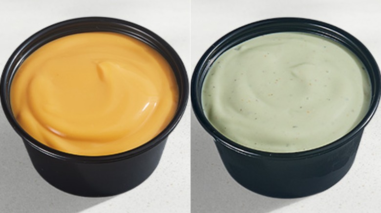 Black container of nacho cheese sauce and black container of avocado ranch sauce