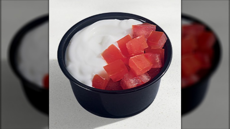Black container with sour cream and tomatoes