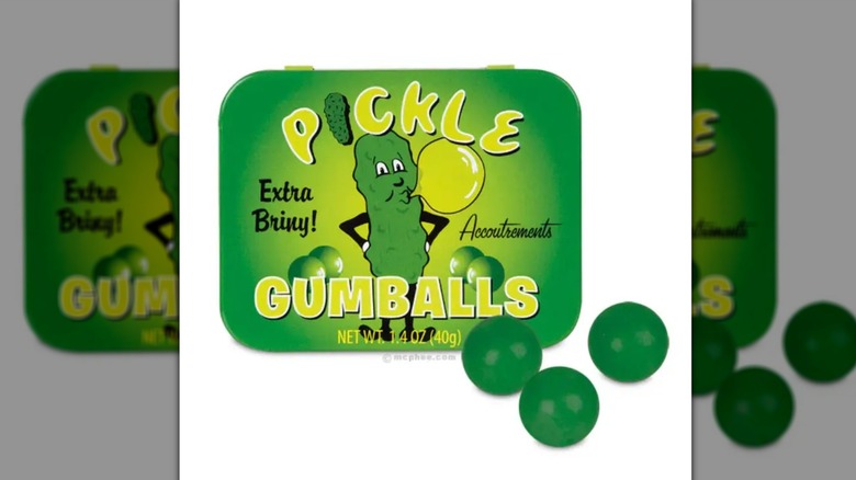 Tin of pickle gum balls next to three green gum balls on white background