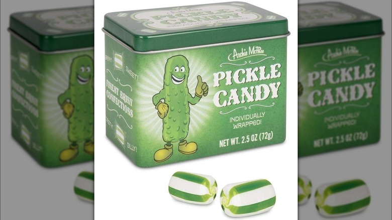 Green tin of Archie McPhee Pickle Candies next to two hard candies