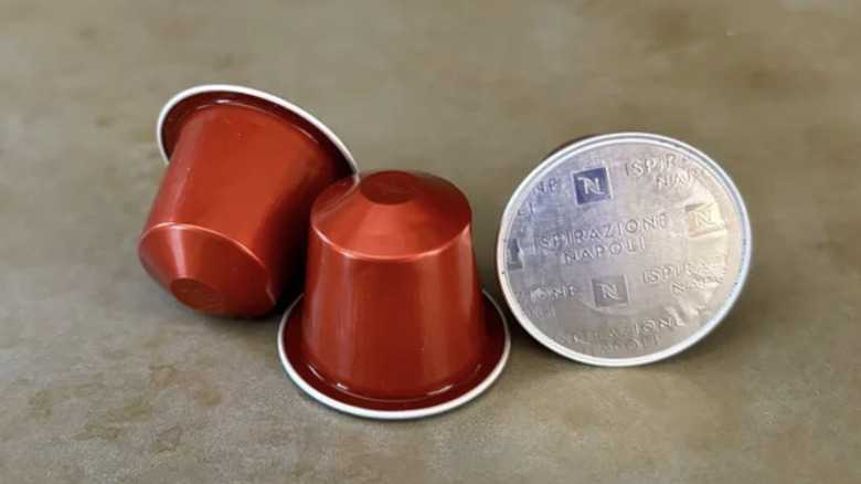Three red Nespresso capsules on a surface, one is on its side