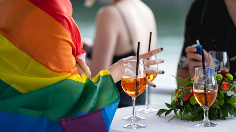 Woman wrapped in pride flag drinking wine